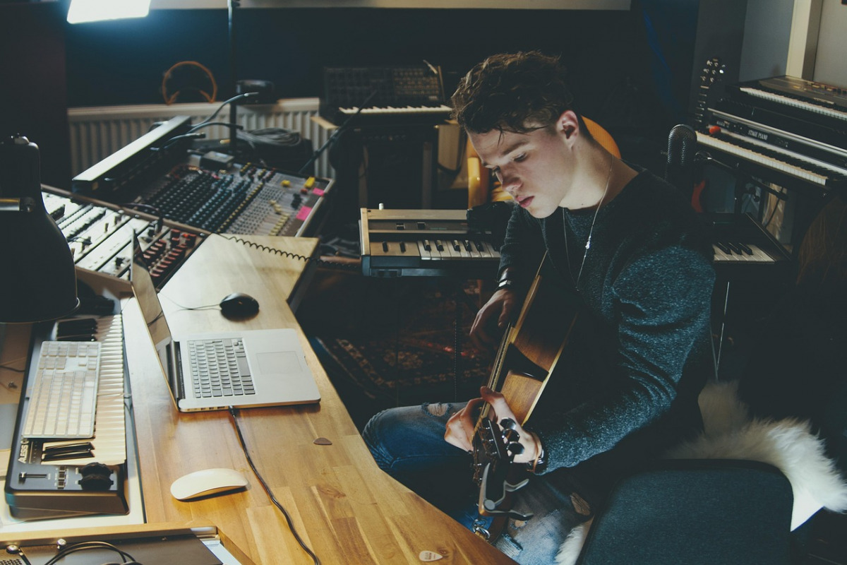songwriter composing with guitar and laptop